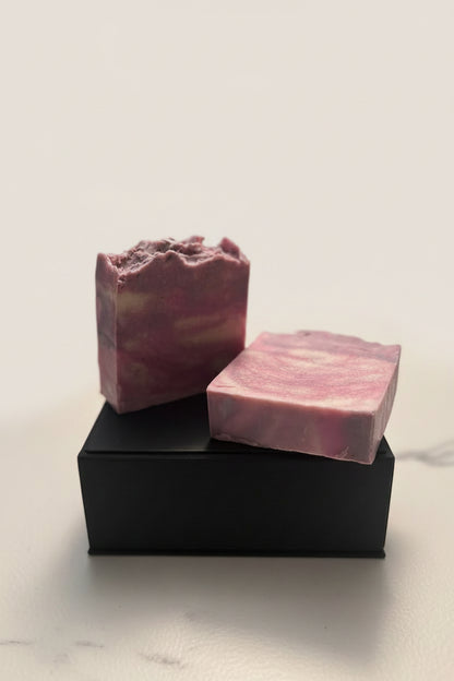 Two pink soap bars on a black stand against a light background