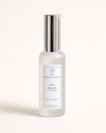 A frosted glass perfume bottle with a reflective silver cap, featuring a white label with blue text that reads 'ICB Boutique & Designs Luna Moeris Eau de Toilette'.