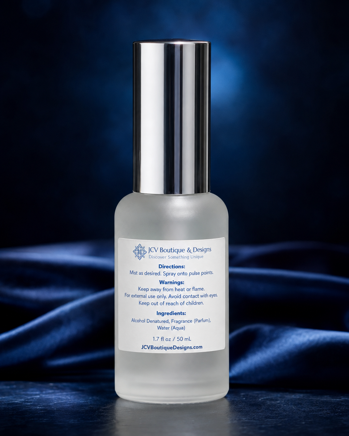 A 1.7 fl oz (50 ml) bottle of body spray by K&V Boutique & Designs, featuring a frosted glass body and a shiny silver cap, set against a dark blue satin background.