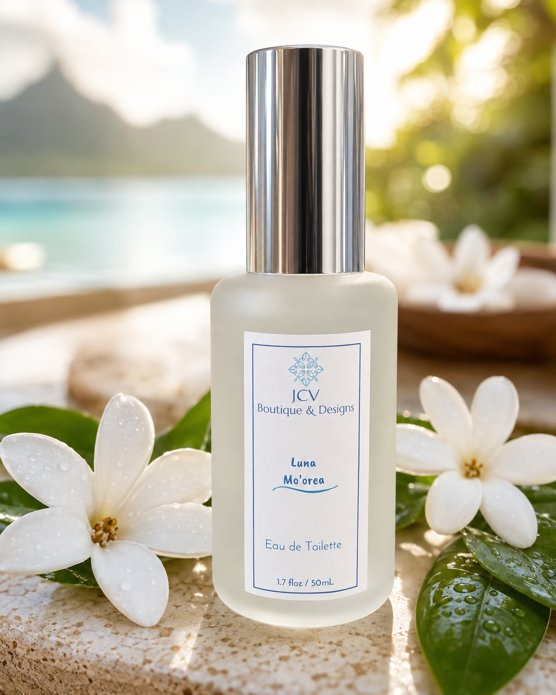 A frosted glass perfume bottle with a silver cap, labeled 'ICV Boutique & Designs Luna Mo'aren Eau de Toilette', styled outdoors with white flowers and green leaves in the foreground and a tropical beach background.